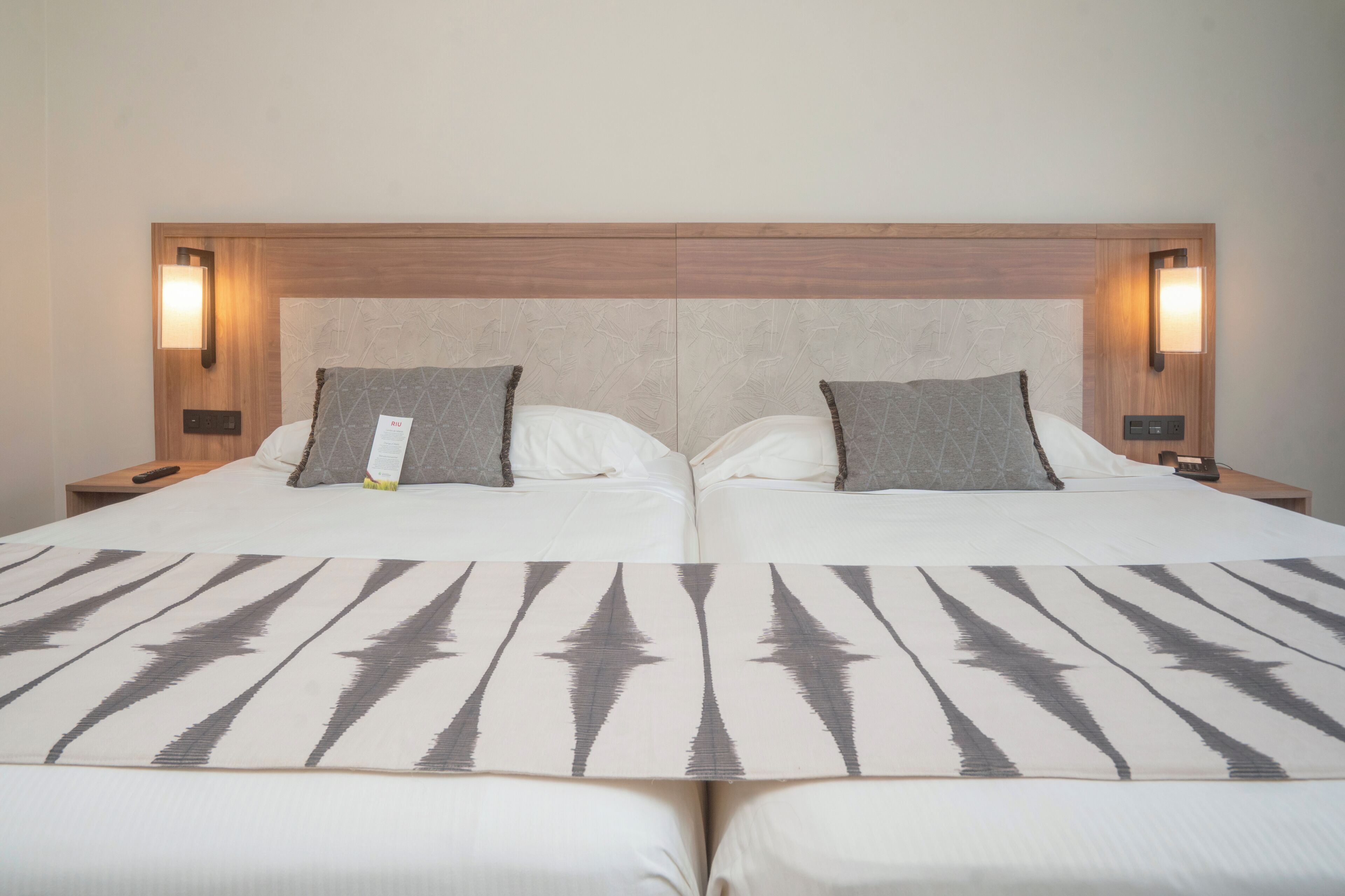 A double bed with a patterned bedspread, two pillows, and bedside lamps.