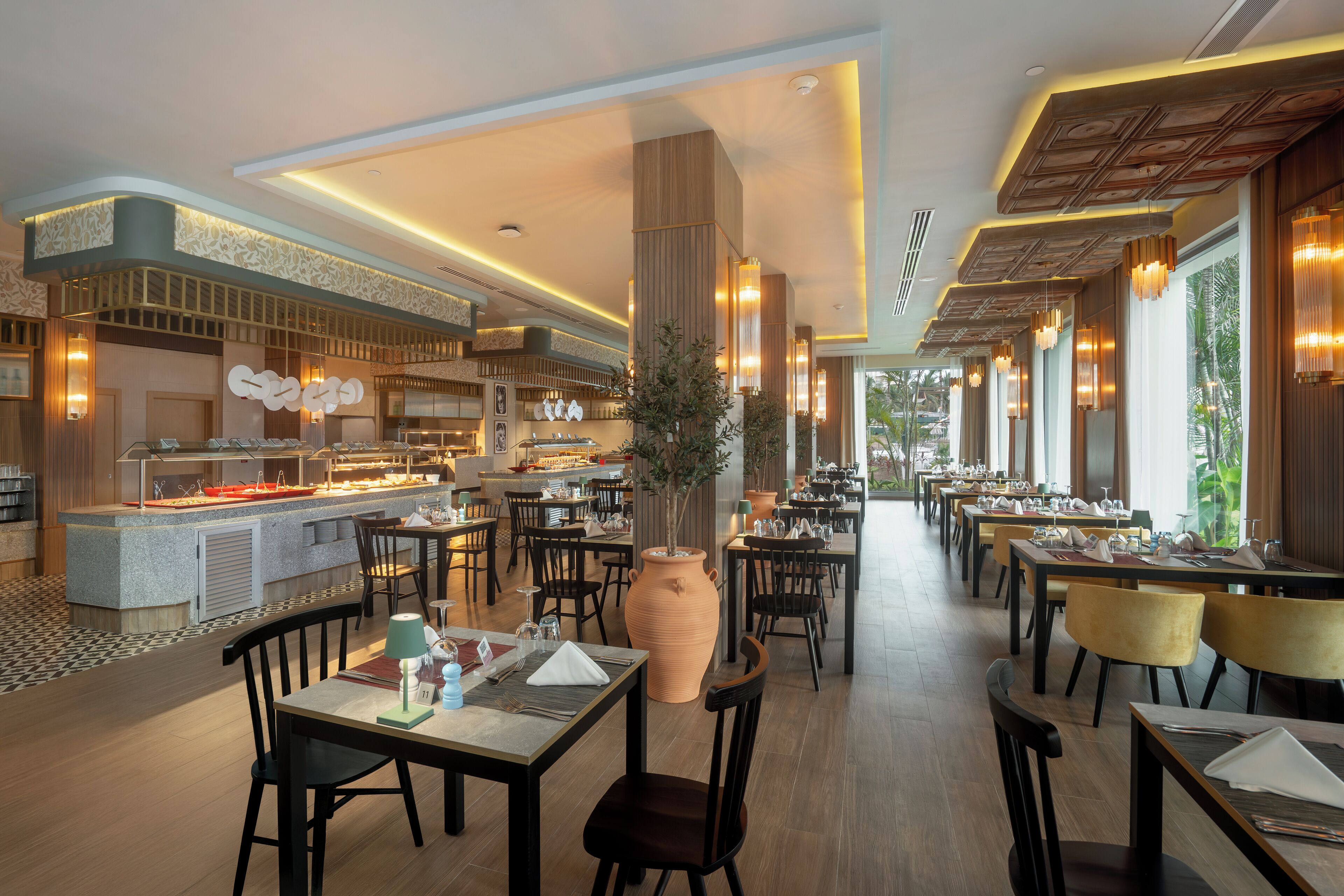 A modern restaurant with a central bar, multiple dining tables, and a large decorative vase.