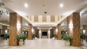 A spacious lobby with high ceilings, large wooden columns, and potted plants. - Riu Flamingos - All Inclusive (Nuevo Nayarit)
