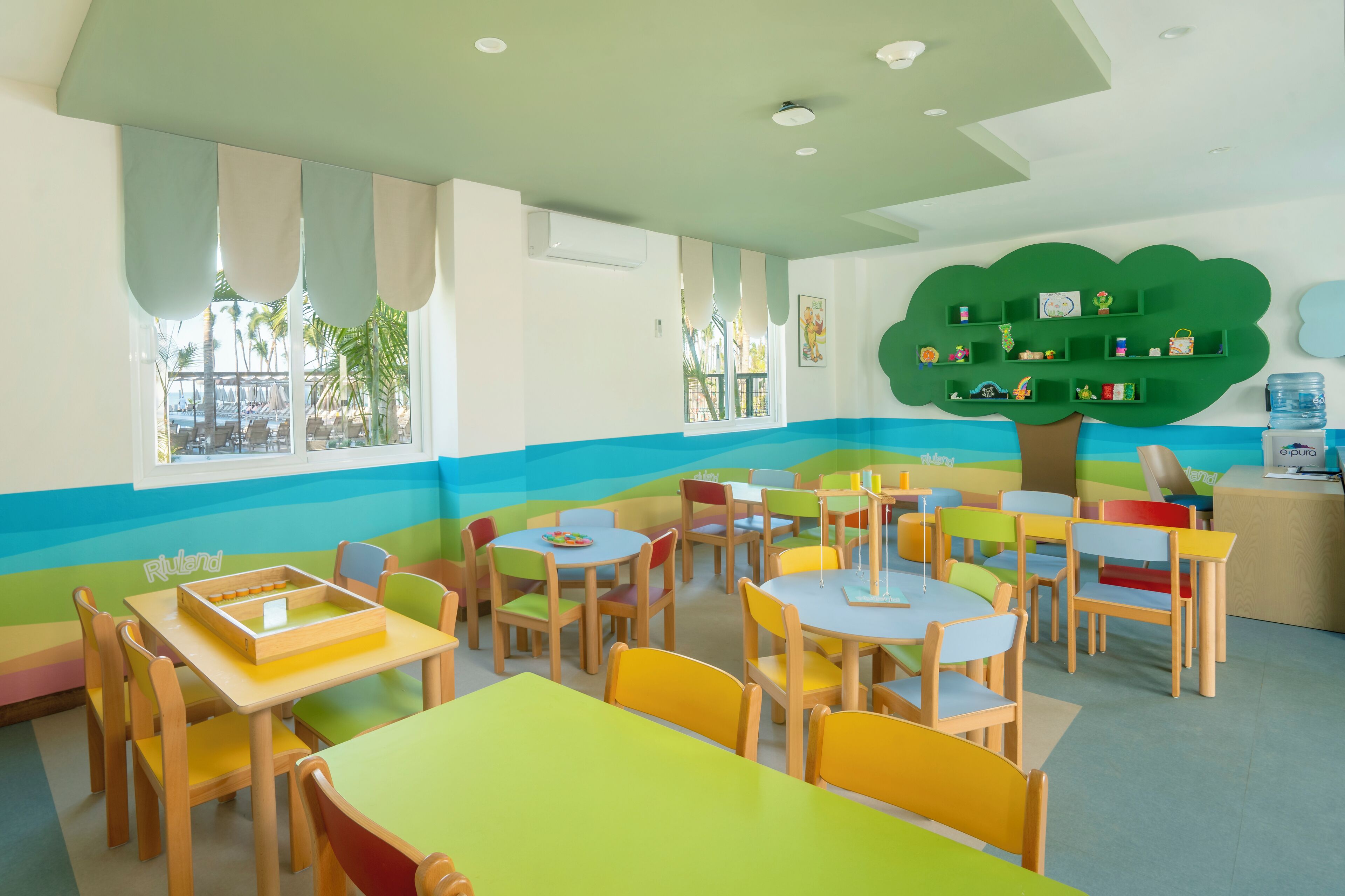 Un cuarto de juegos infantil con muebles coloridos y un estante en forma de árbol.