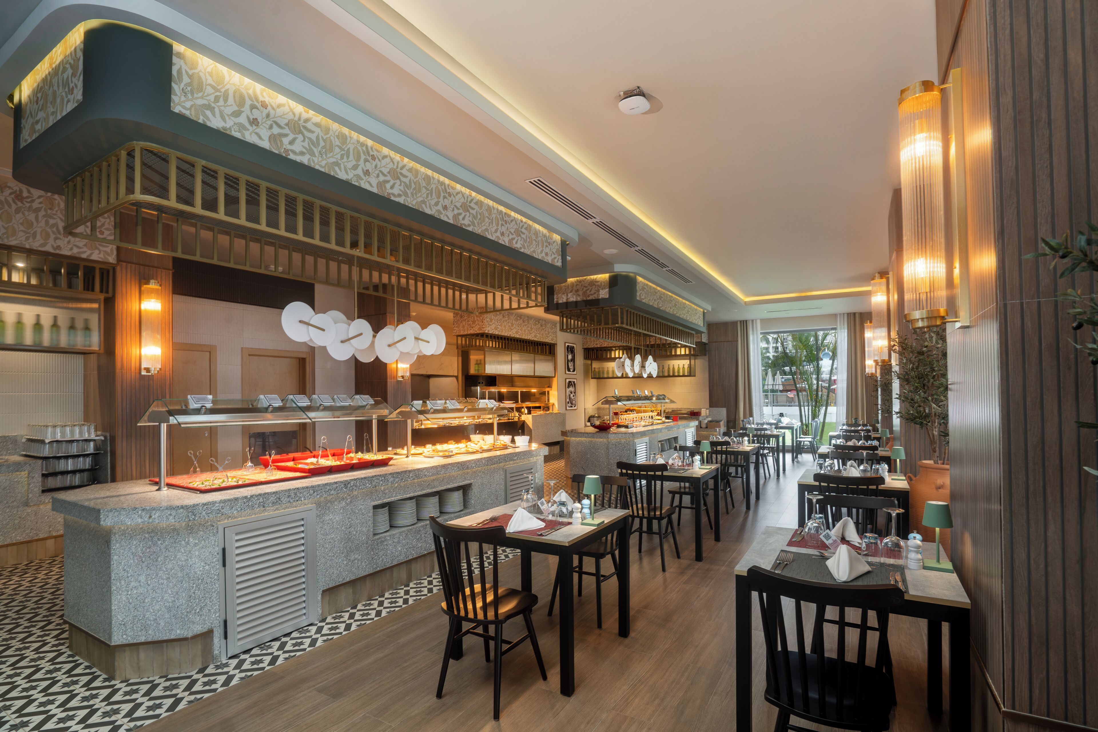 A modern restaurant with a buffet area, multiple dining tables, and a patterned floor.