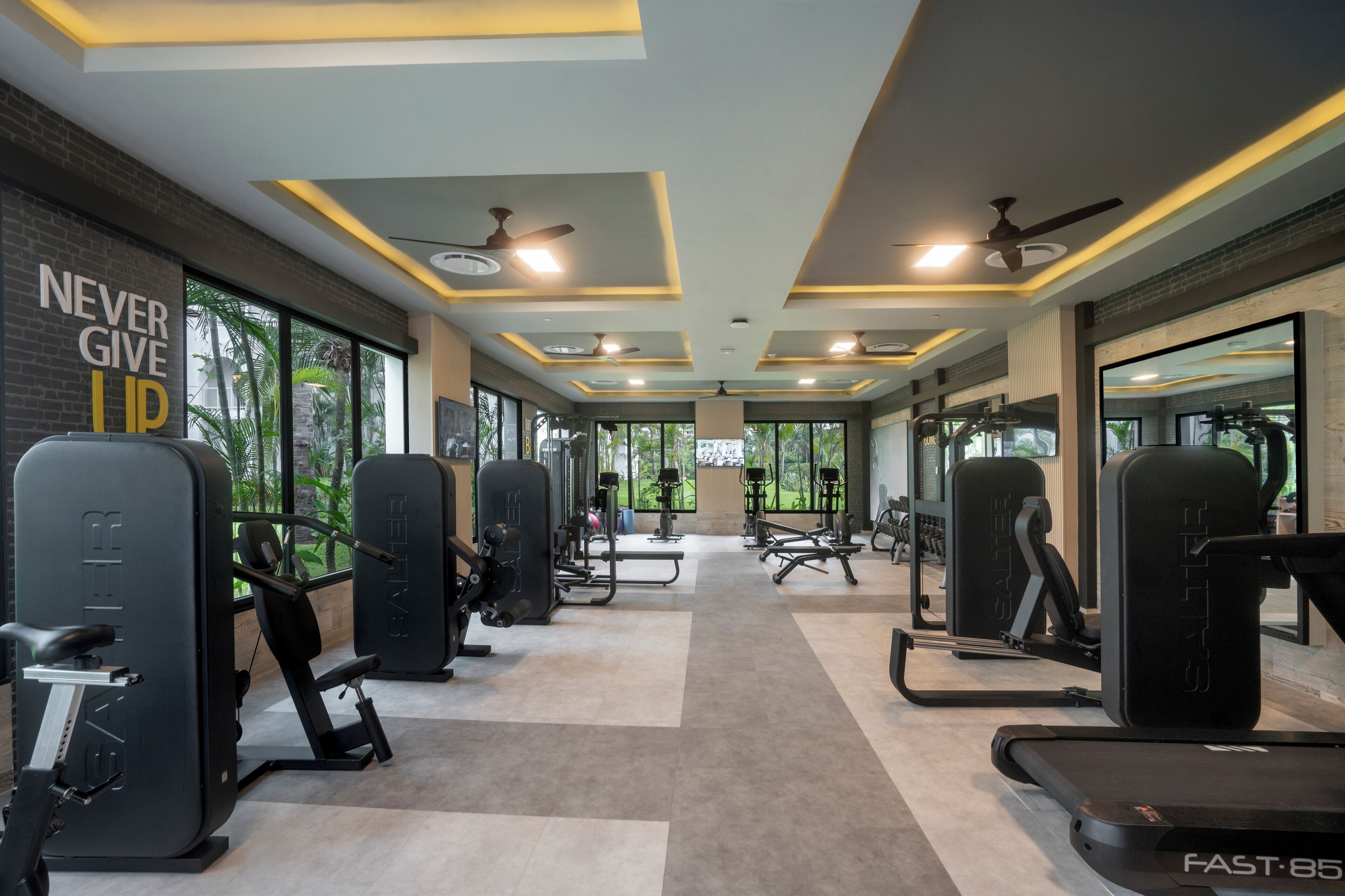 Une salle de sport équipée de matériel d’exercice, dotée d’un mur d’inspiration et de grandes fenêtres.