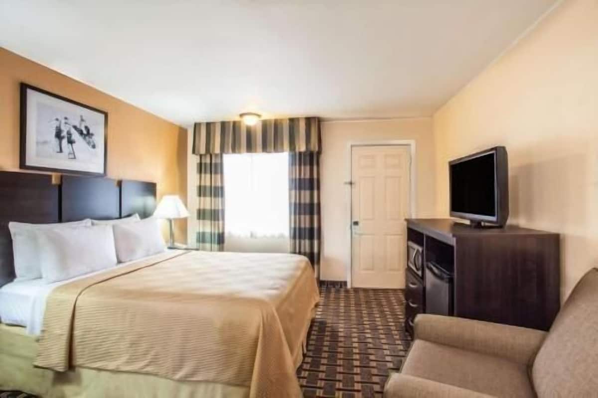 A hotel room with a bed, a television, a desk, and a chair.