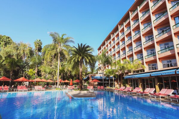 Una piscina al aire libre, sombrillas, tumbonas