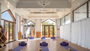 A spacious room with large windows, a wooden floor, and purple exercise mats. - Es Saadi Marrakech Resort Hotel (Marrakech)