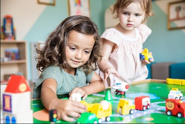 Two children playing with toy vehicles on a table.