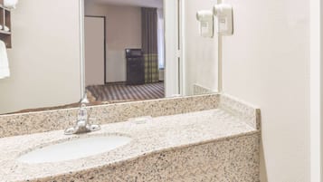 A bathroom with a granite countertop sink, a mirror, and a towel rack.