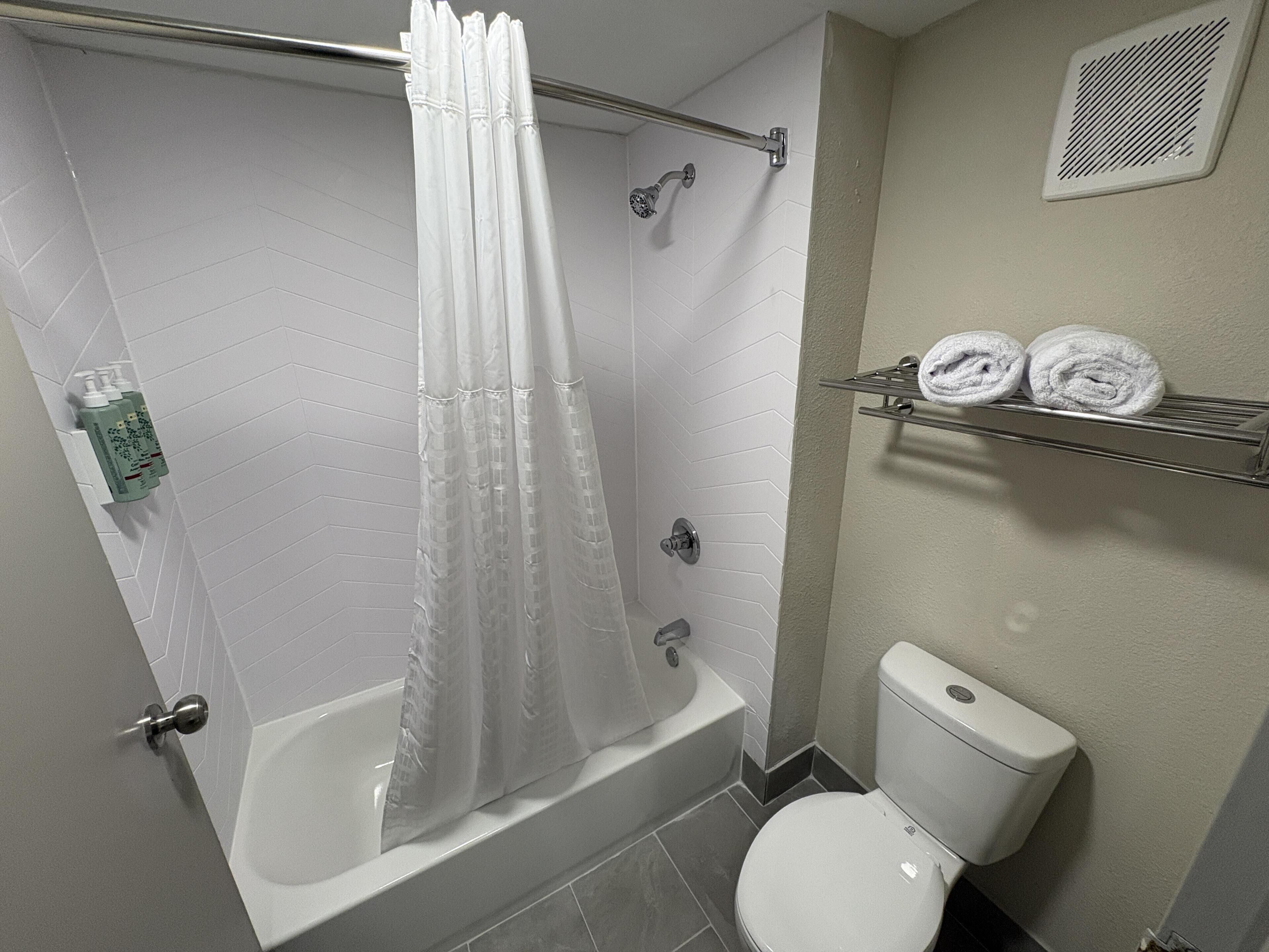 A bathroom with a shower, bathtub, toilet, and towel rack.