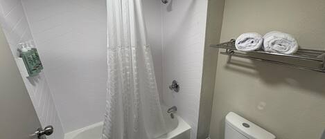 A bathroom with a shower, bathtub, toilet, and towel rack.