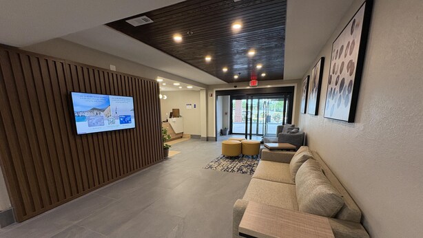 A modern lobby with a reception desk, seating area, and a television screen. - Best Western Spartanburg I-26 (Spartanburg)