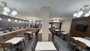 A modern restaurant with high tables and chairs, a counter with a coffee machine, and a patterned wall. - Best Western Spartanburg I-26 (Spartanburg)