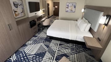 Una habitación de hotel con cama, escritorio, televisión y obras de arte en las paredes.