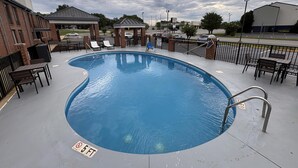A swimming pool with lounge chairs and tables, surrounded by brick buildings and a covered seating area. - Best Western Spartanburg I-26 (Spartanburg)