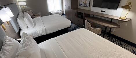 A hotel room with two beds, a desk, a television, and a chair.
