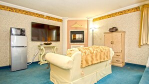 Une pièce avec un canapé beige, une petite table, un meuble, un four à micro-ondes et une cheminée.