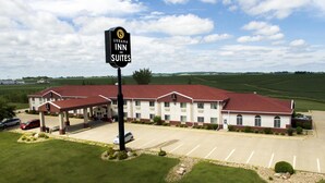 Un hôtel avec un toit rouge et des murs blancs, sur lequel on peut voir une enseigne indiquant « Urbana Inn and Suites ».