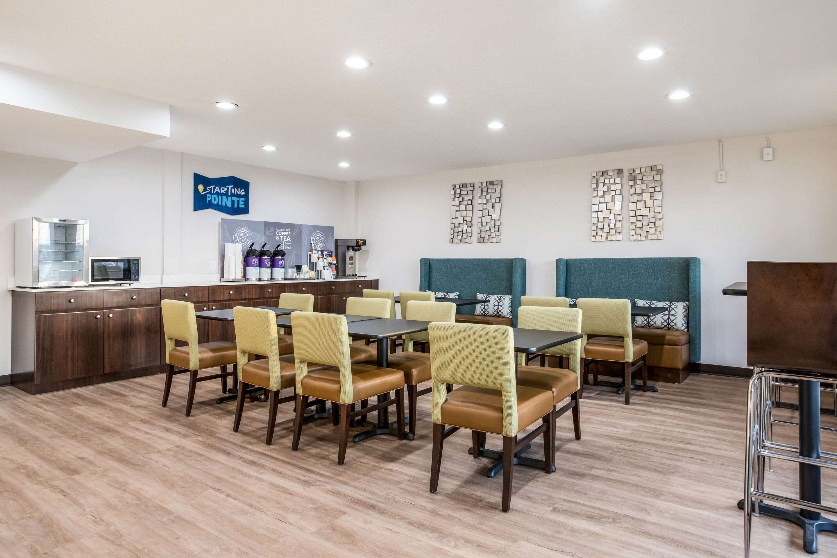 A hotel dining area with tables and chairs, a coffee station, and a reception desk.