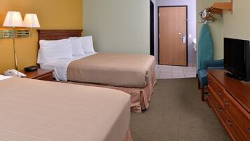 A hotel room with two beds, a desk with a telephone, a television, and a door leading to another room.
