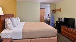 A hotel room with a bed, a television, a desk, and a dresser. - Americas Best Value Inn Seymour (Seymour)