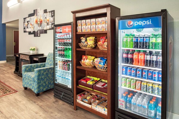 Zona de máquinas expendedoras con Pepsi, Coca-Cola y otras bebidas, además de aperitivos y una silla decorativa.