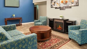 Un salon avec des canapés à motifs floraux bleus, une table basse en bois, une cheminée et un tapis.