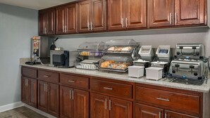 Une cuisine avec des meubles en bois, un four à micro-ondes, un grille-pain et un présentoir pour les aliments.