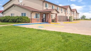 Un motel à deux étages, avec une façade en briques, un parking doté de places réservées aux personnes handicapées et une pelouse bien entretenue.