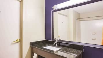 A bathroom with a sink, mirror, and door.
