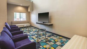 Una habitación con sillas moradas, un televisor en un estante y un suelo estampado.