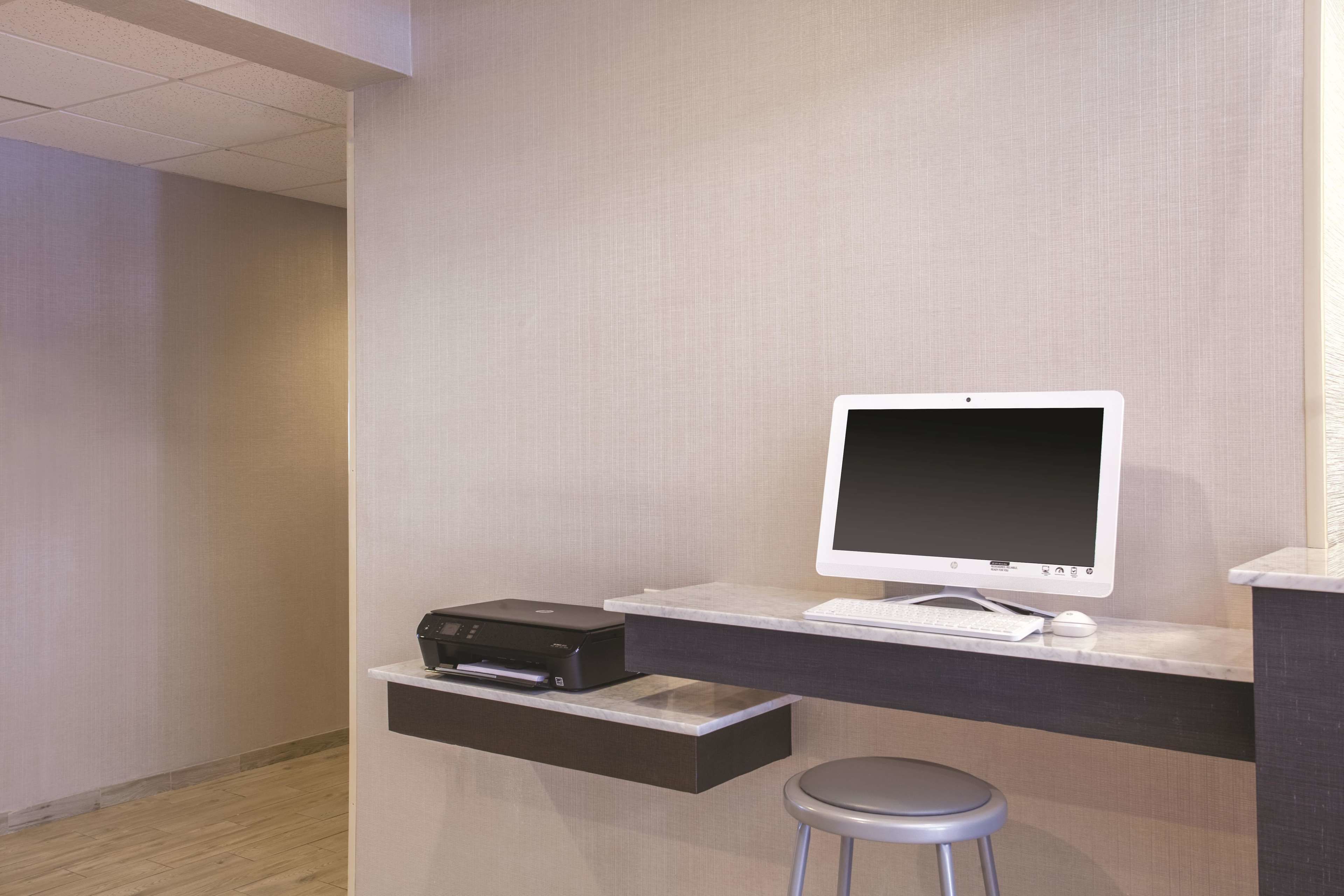 A modern office space with a desktop computer, printer, and a stool.