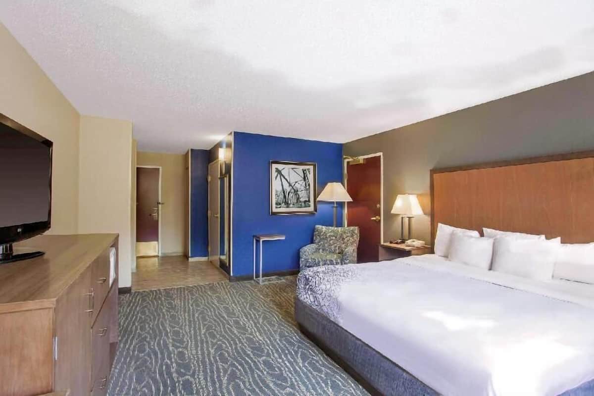 Hotelkamer met een bed, een televisie, een bureau, een stoel, een lamp en een schilderij aan de muur.