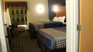 A hotel room with two beds, a desk, a chair, and a window with curtains.