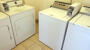 A laundry room with three white front-loading washing machines.