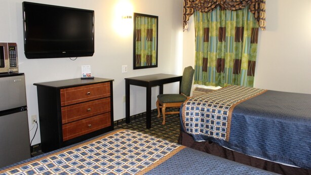 Een hotelkamer met twee bedden, een bureau, een stoel, een televisie en een koelkast.