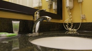 A bathroom sink with a chrome faucet, a mirror above it, and toiletries on the countertop.