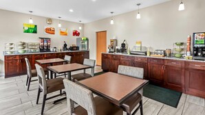 A modern kitchen with wooden cabinets, a dining area with tables and chairs, and a refrigerator. - Quality Inn Sawyer (Sawyer)