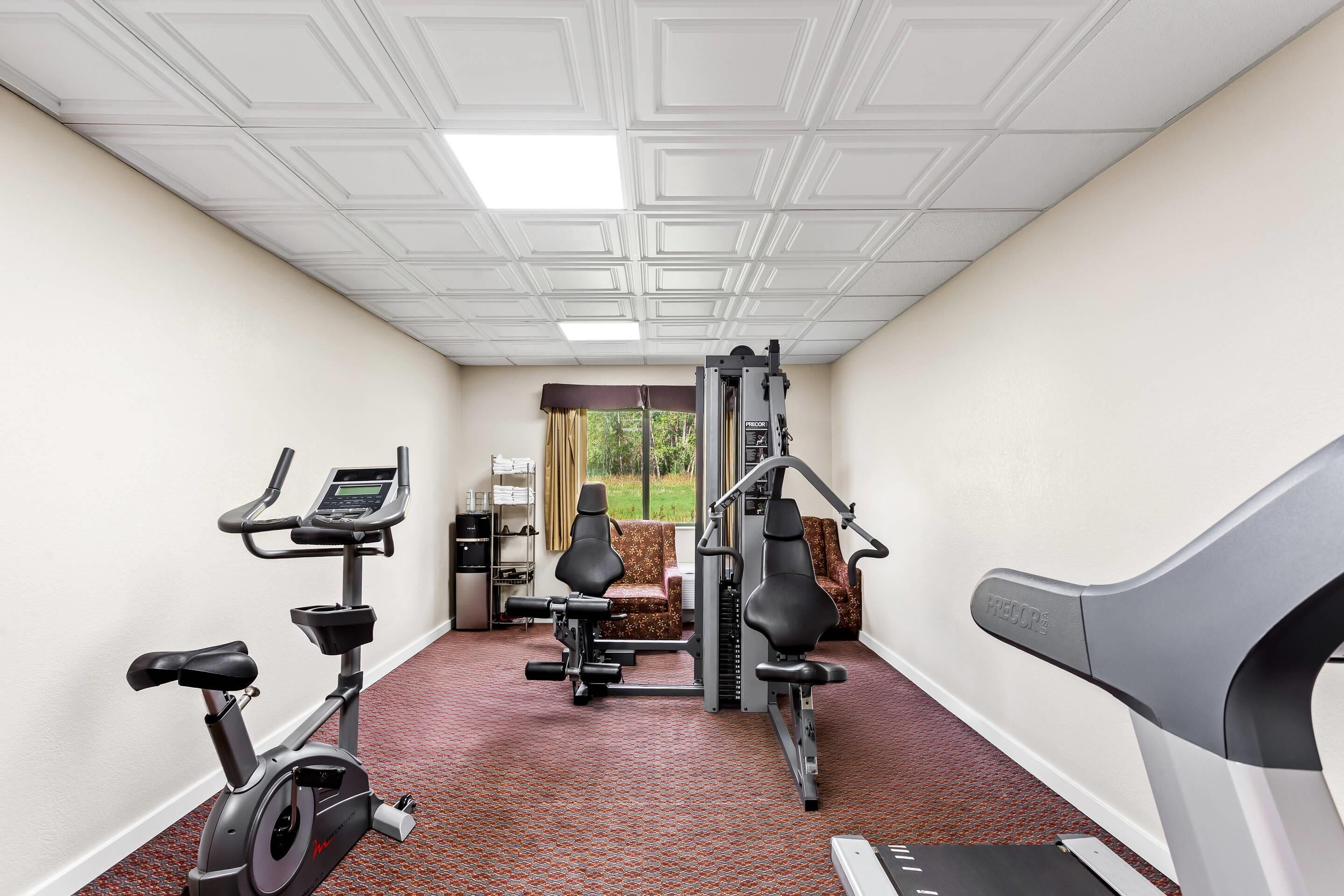 A hotel fitness room with an exercise bike, elliptical, and weight machine.