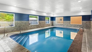 An indoor swimming pool with clear blue water, surrounded by stone walls and large windows. - Quality Inn Sawyer (Sawyer)