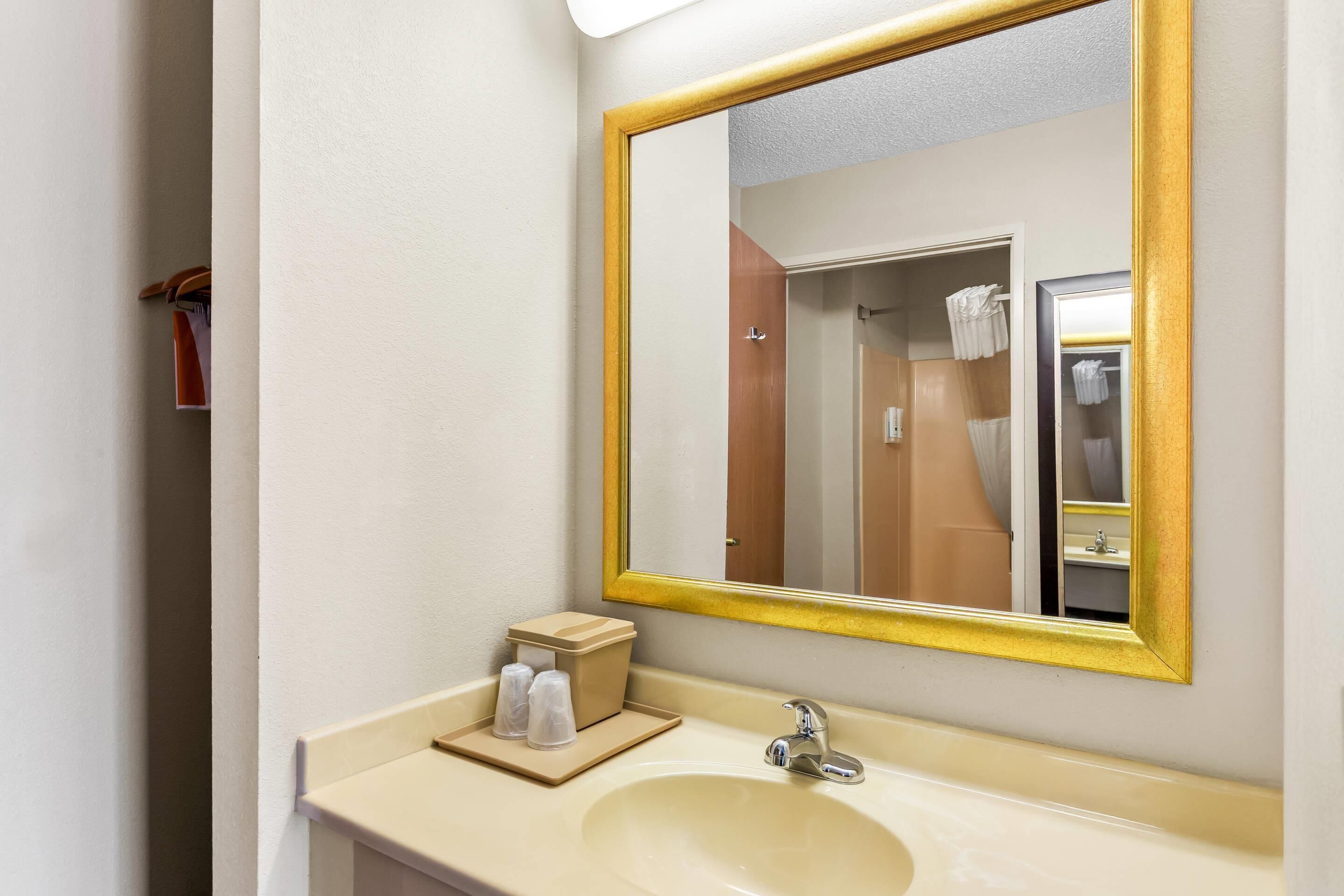 A bathroom with a sink, mirror, and towel rack.