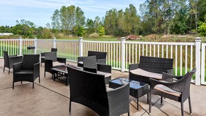 An outdoor patio area with wicker furniture and a white fence. - Quality Inn Sawyer (Sawyer)