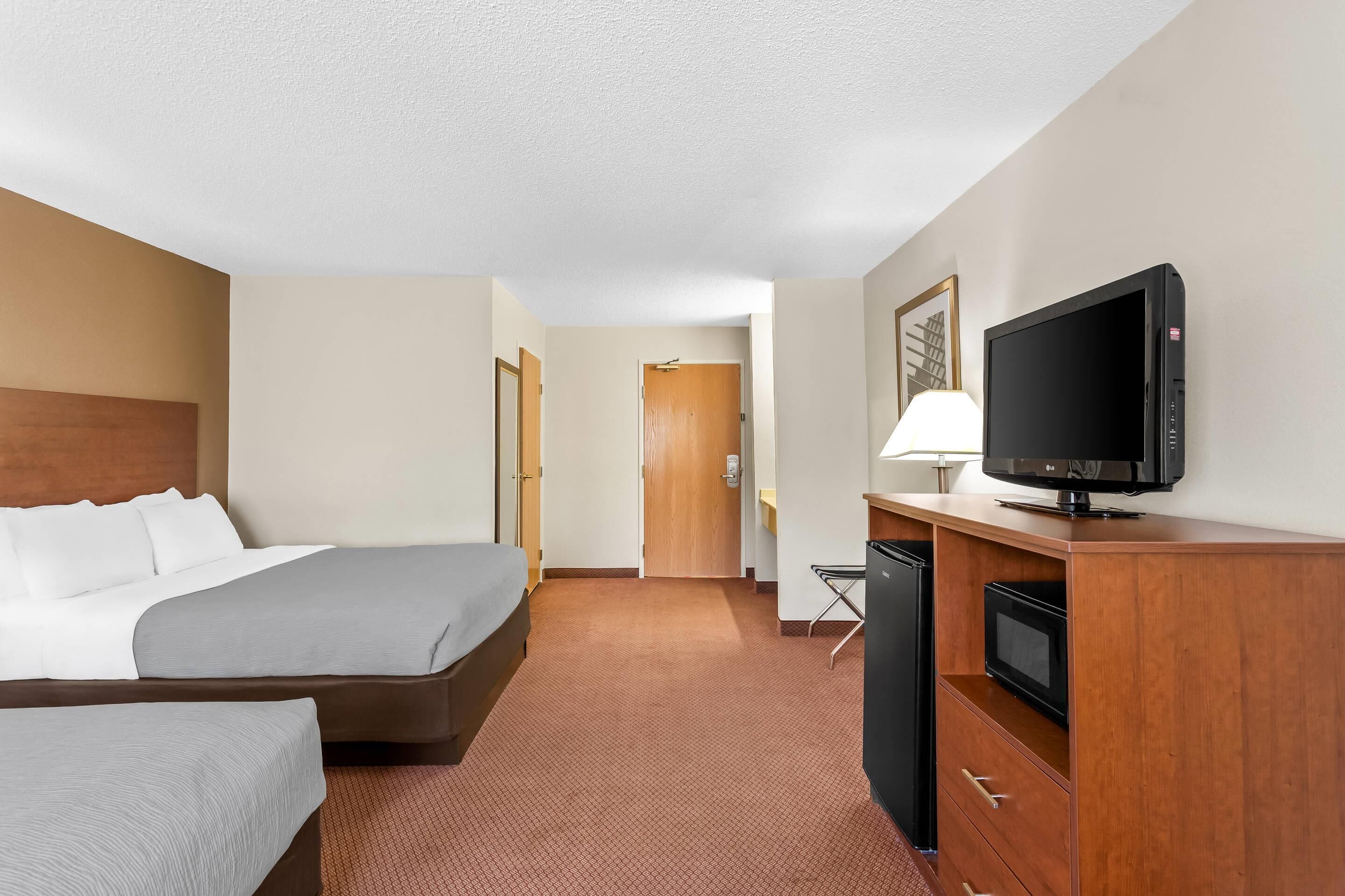 Una habitación de hotel con cama, televisión, escritorio y puerta.