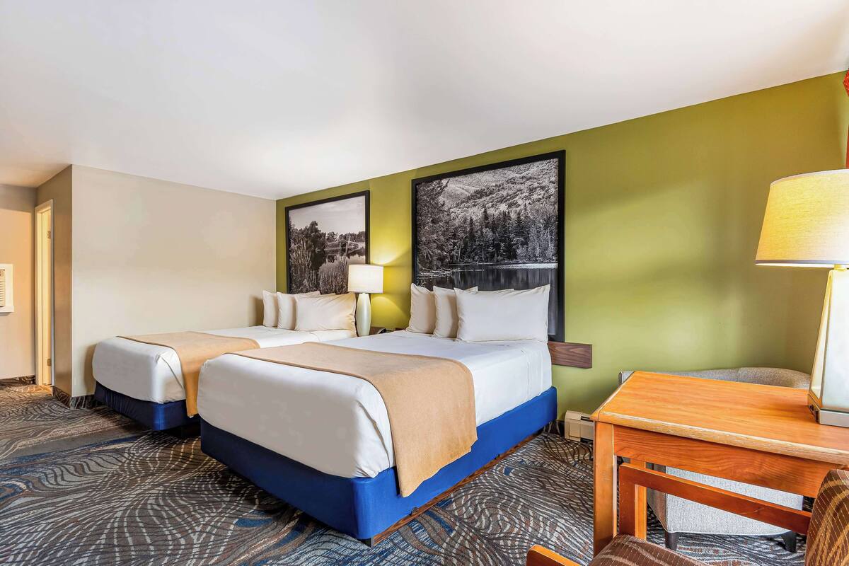 Une chambre d’hôtel avec deux lits, un bureau et une chaise.