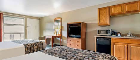 Habitación de hotel con dos camas, un escritorio, un televisor, un microondas y armarios de madera.