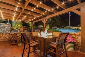An outdoor patio with a wooden pergola, stone walls, and a fire feature. - Super 8 by Wyndham Lake George/Downtown (Lake George)