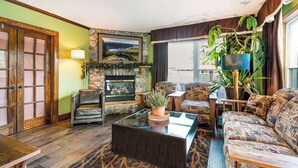 A cozy living room with a fireplace, comfortable seating, and a large window.