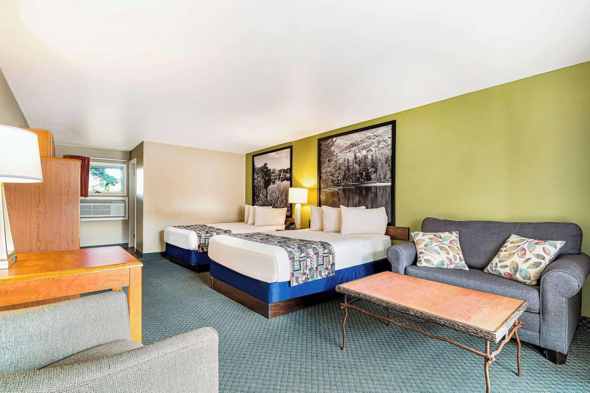 Une chambre d’hôtel avec deux lits, un canapé, une petite table et une fenêtre.