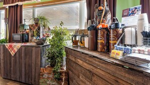 A rustic bar area with a wooden counter, coffee machines, and a variety of coffee cups and mugs.