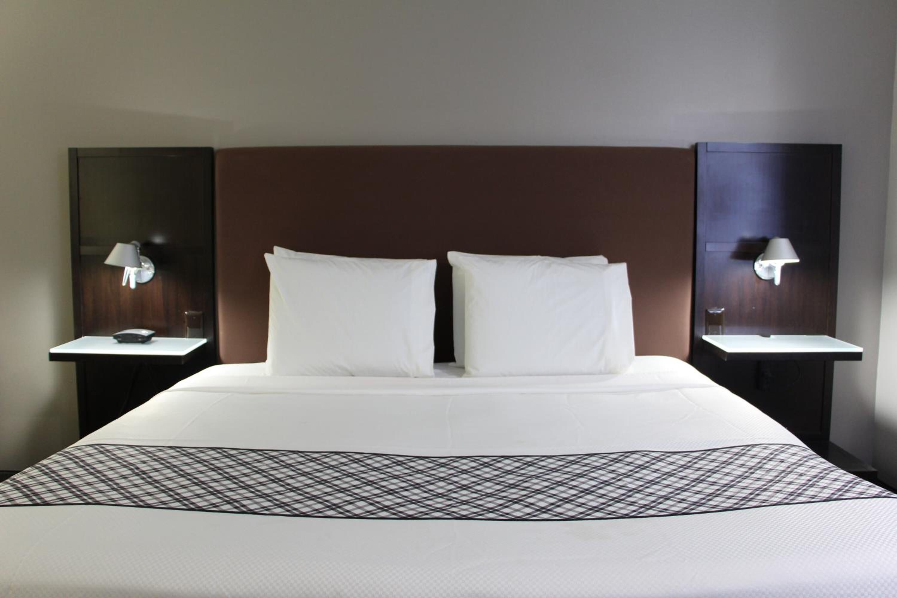 A hotel room with a large bed, two bedside tables with lamps, and a headboard.