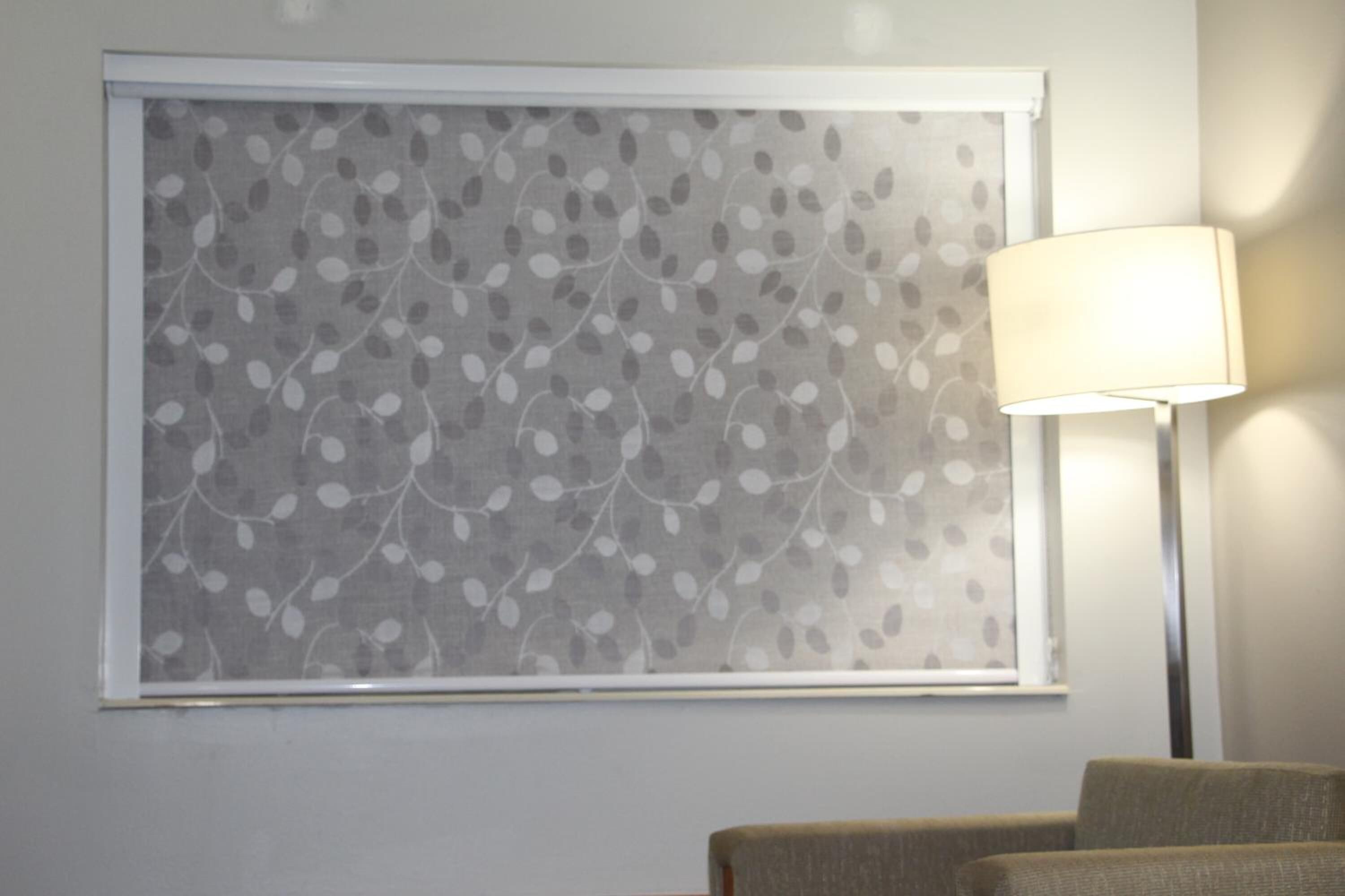 A room with a window featuring a leaf pattern, a lamp, and a sofa.