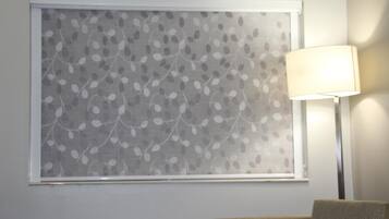A room with a window featuring a leaf pattern, a lamp, and a sofa.
